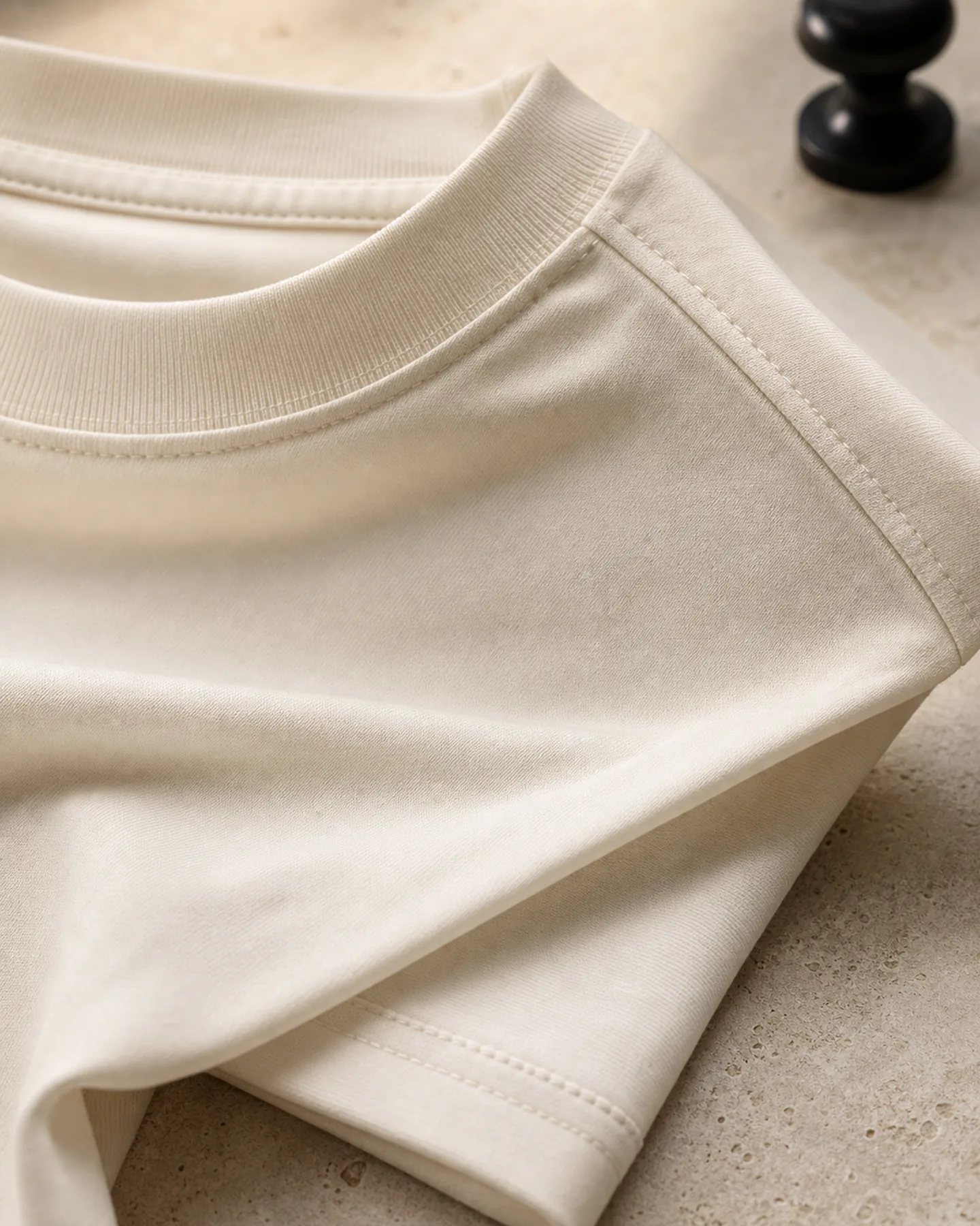 Close detail of collar rib, shoulder seam, stitching, and ivory Supima cotton fabric